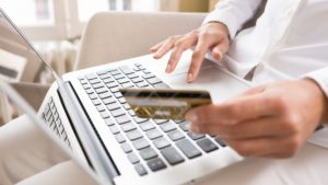 Woman holding a credit card and using computer, online shopping