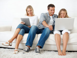 Full length of father assisting daughter in using laptop while mother holding tablet PC