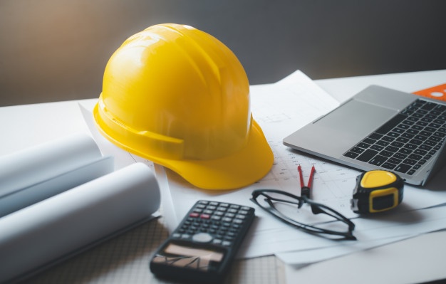 yellow-hard-hat-safety-helmet-on-a-work-desk-with-a-design-plan-of-the-house_11304-1713